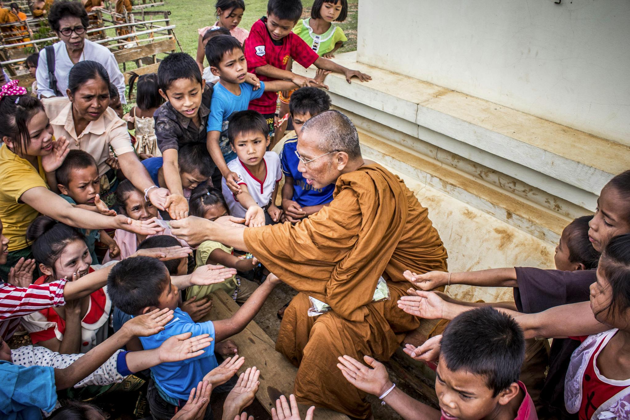 A Buddhist monk sharing gifts with children, capturing a moment of compassion and cultural tradition.
